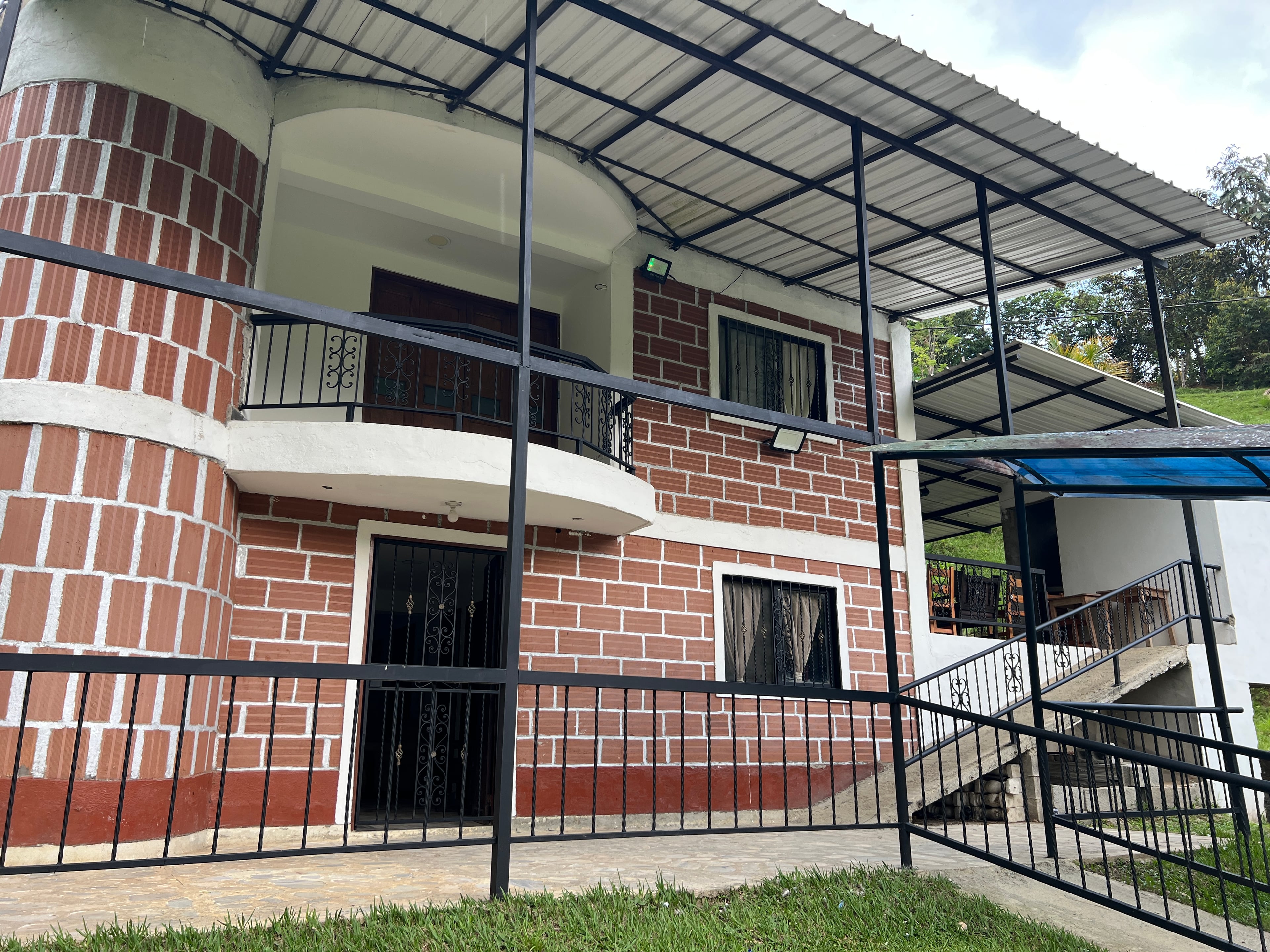 Fachada de la casa de Bethel: dos pisos de ladrillo con balcón y techo metálico.