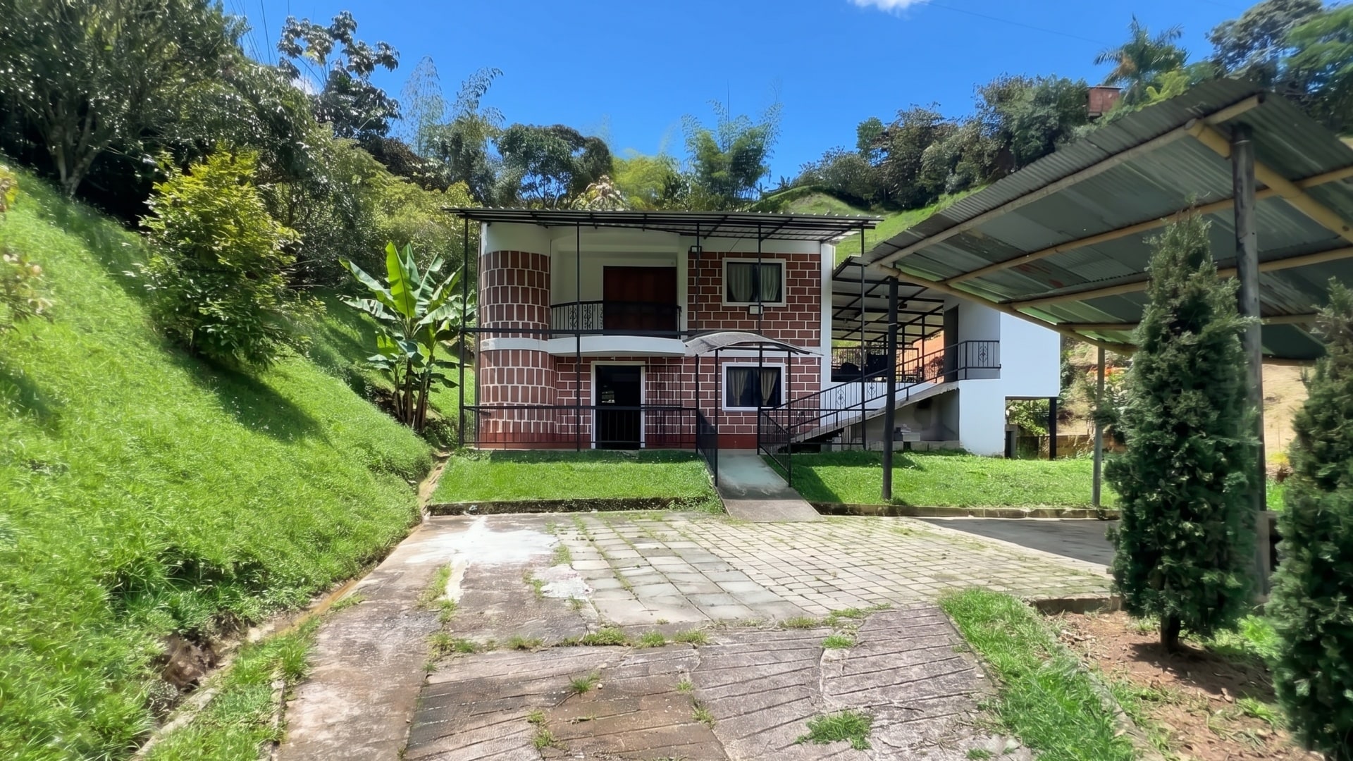 La casa de Bethel a pleno día, con el cielo despejado y la montaña verde alrededor.